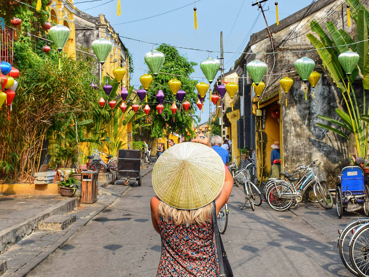 Tourist wearing straw hat in the middle of road in Hoi An Ancient Town, Hoi An tour